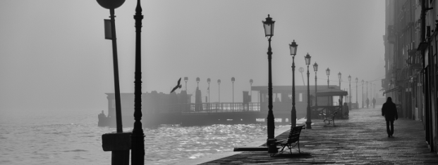 A greyscale photograph of a boardwalk on a foggy day.